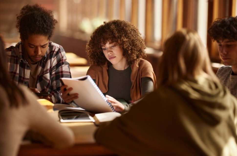 A group of students sitting around a table in a study space, reviewing notes and working together in a collaborative setting.
