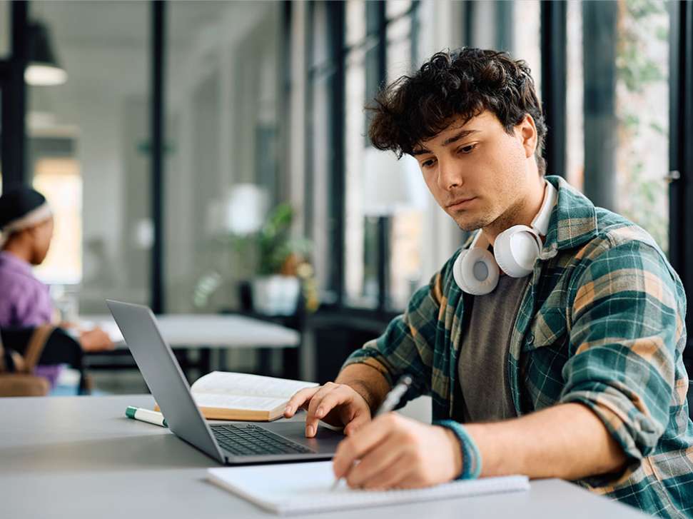 Young male student studying in a library setting.