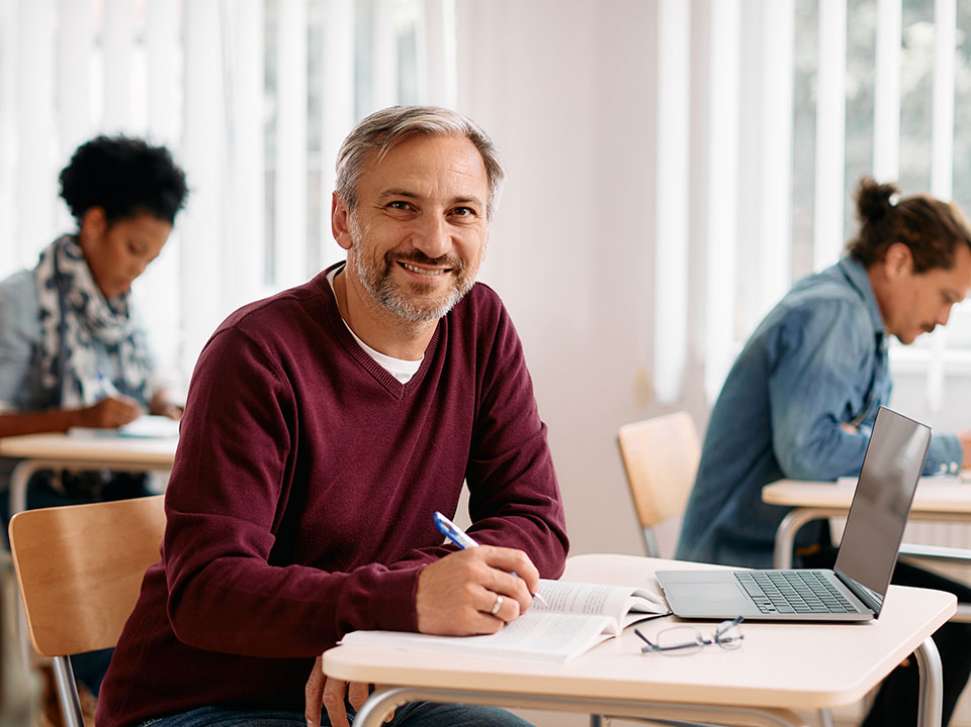 Smiling male mature aged student working at a desk.
