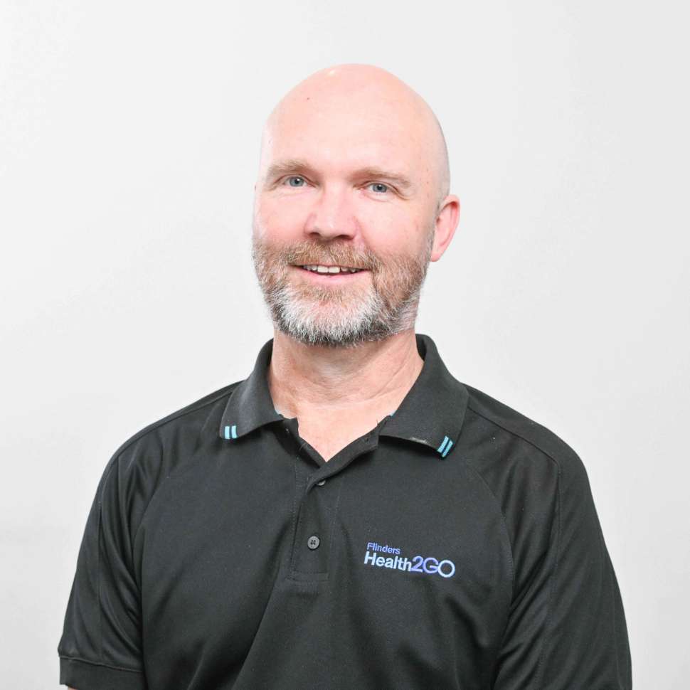 A man wearing a black polo behind a white backdrop