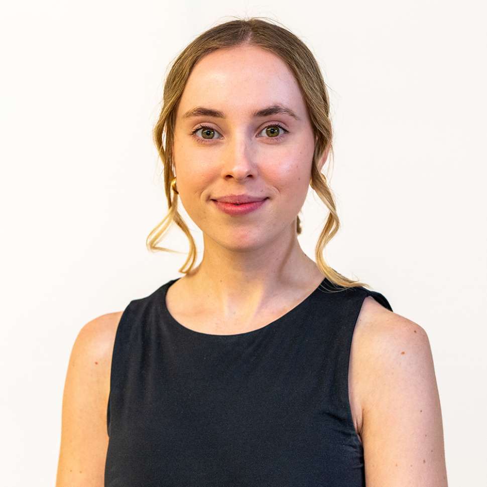 A woman wearing a black top behind a white backdrop