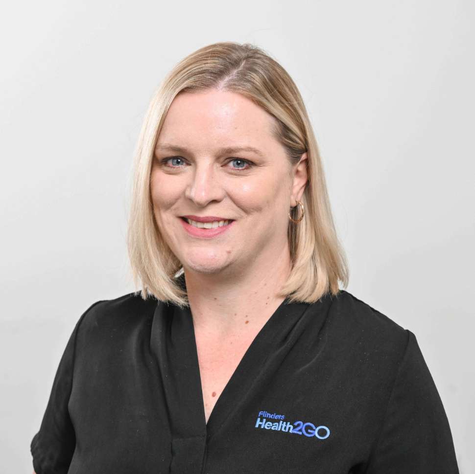 A woman wearing a black polo behind a white backdrop